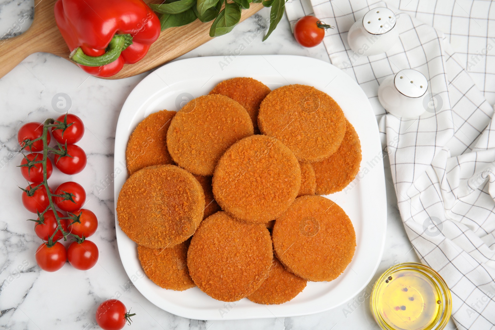 Photo of Delicious fried breaded cutlets, spices and vegetables on white marble table, flat lay