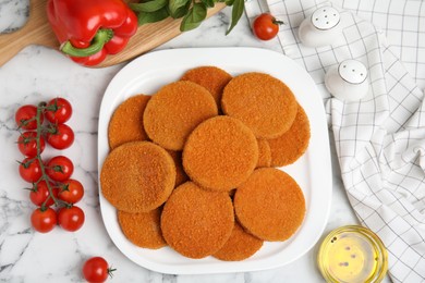 Photo of Delicious fried breaded cutlets, spices and vegetables on white marble table, flat lay