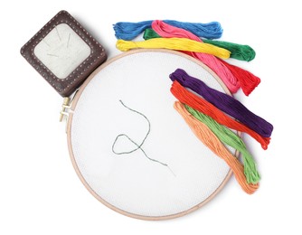 Photo of Colorful threads and different embroidery accessories on white background, top view