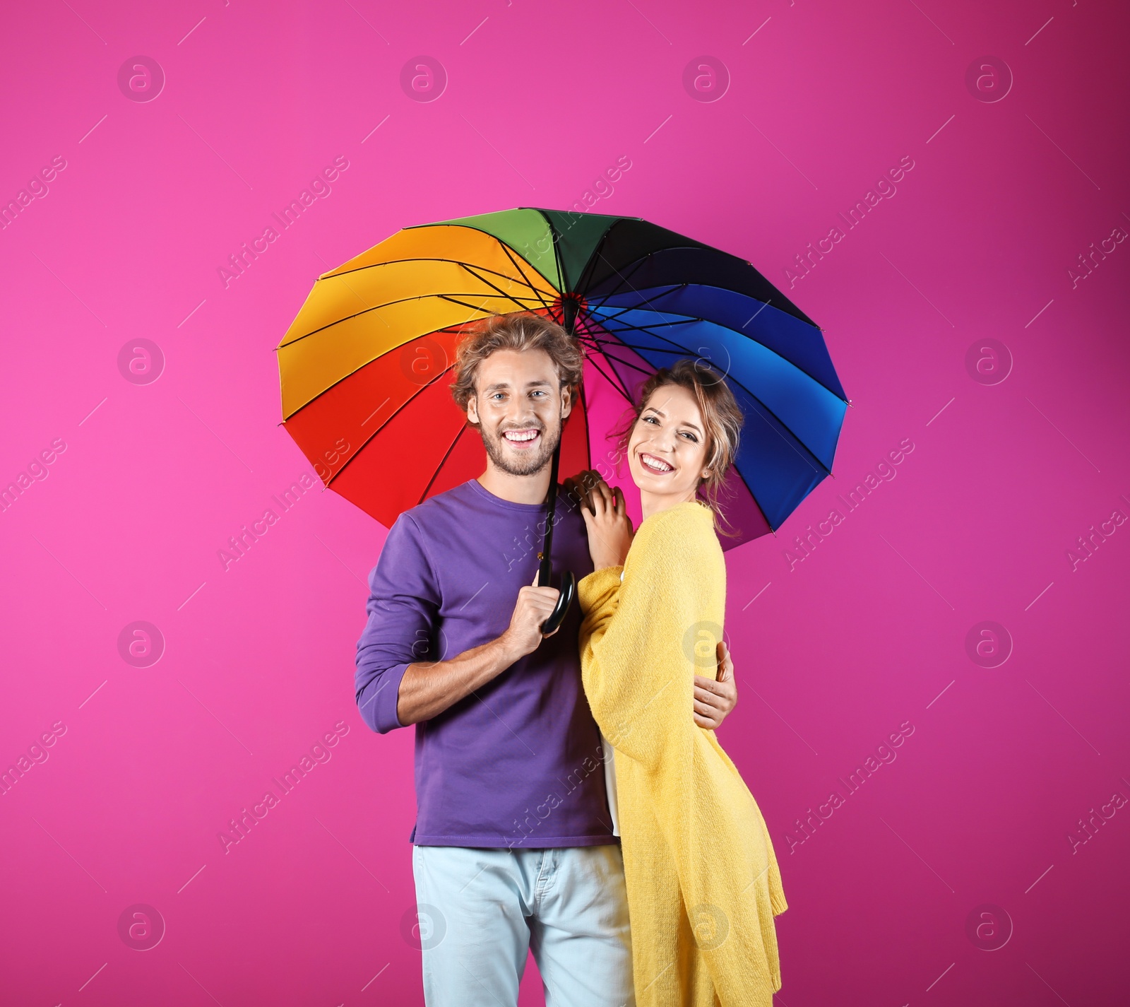 Photo of Couple with rainbow umbrella on color background