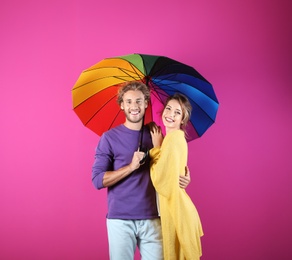 Photo of Couple with rainbow umbrella on color background