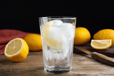 Photo of Soda water with lemon slices and ice cubes on wooden table