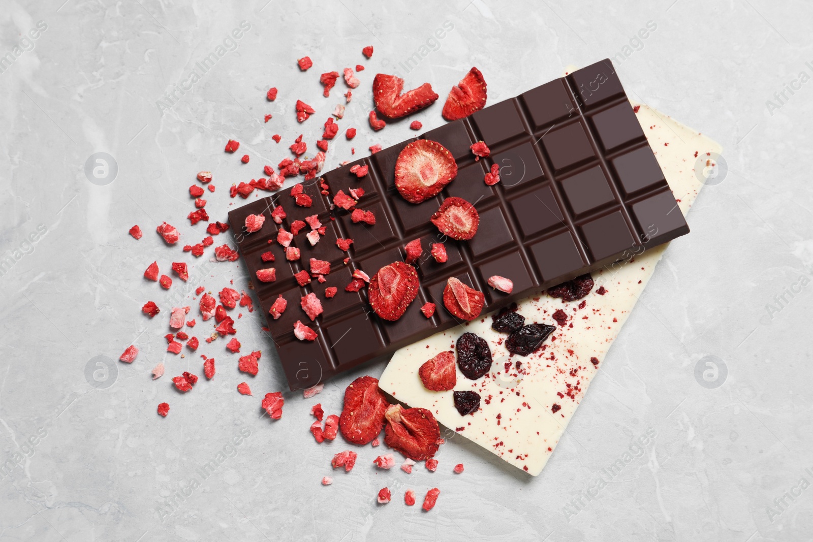 Photo of Different chocolate bars with freeze dried fruits on light marble table, top view