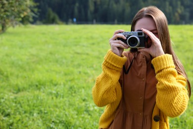 Photo of Woman taking photo with camera on green meadow