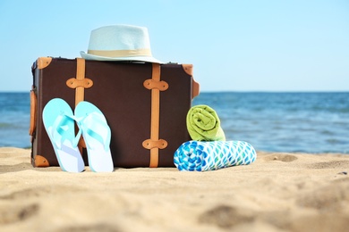 Photo of Suitcase and beach accessories on sand near sea. Space for text