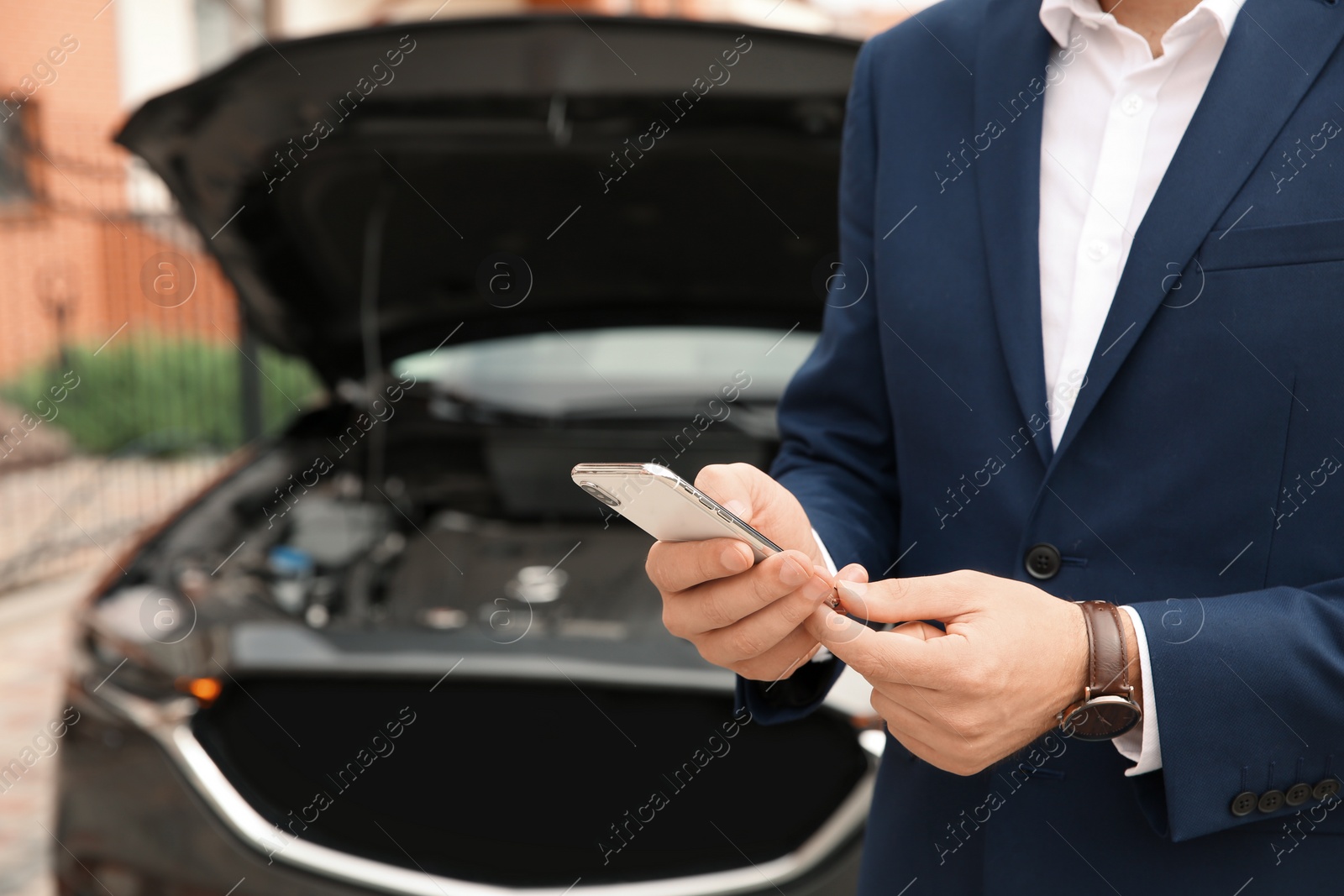 Photo of Man with smartphone near broken car, closeup