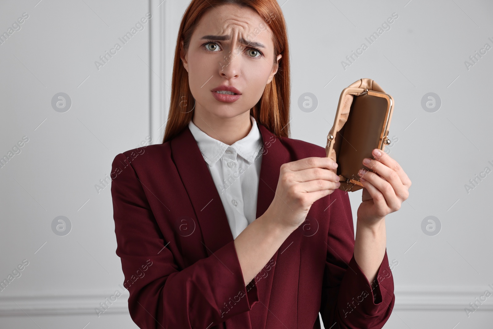 Photo of Upset woman with empty wallet near white wall