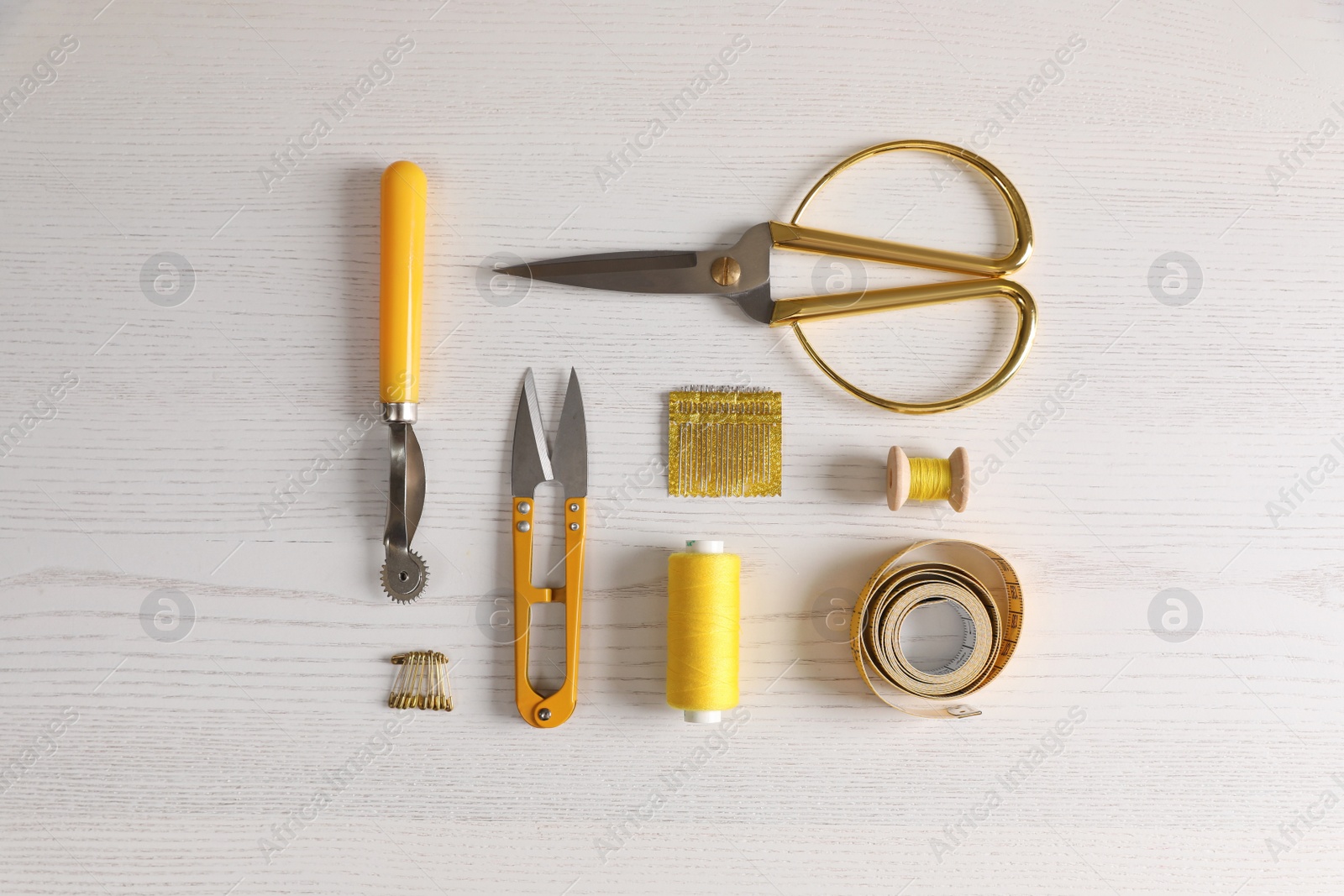 Photo of Set of sewing supplies and accessories on white wooden table, flat lay