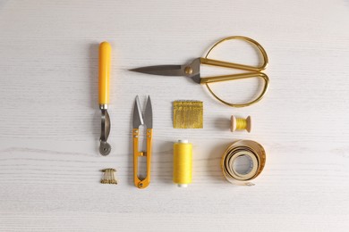 Photo of Set of sewing supplies and accessories on white wooden table, flat lay