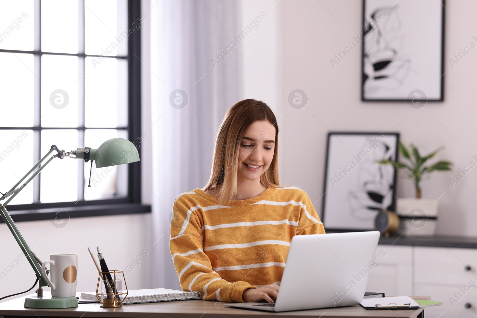 Photo of Teenage girl using laptop at table in her room