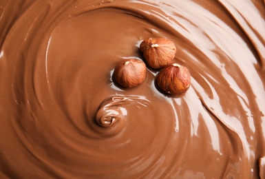 Sweet tasty chocolate cream with hazelnuts as background, closeup