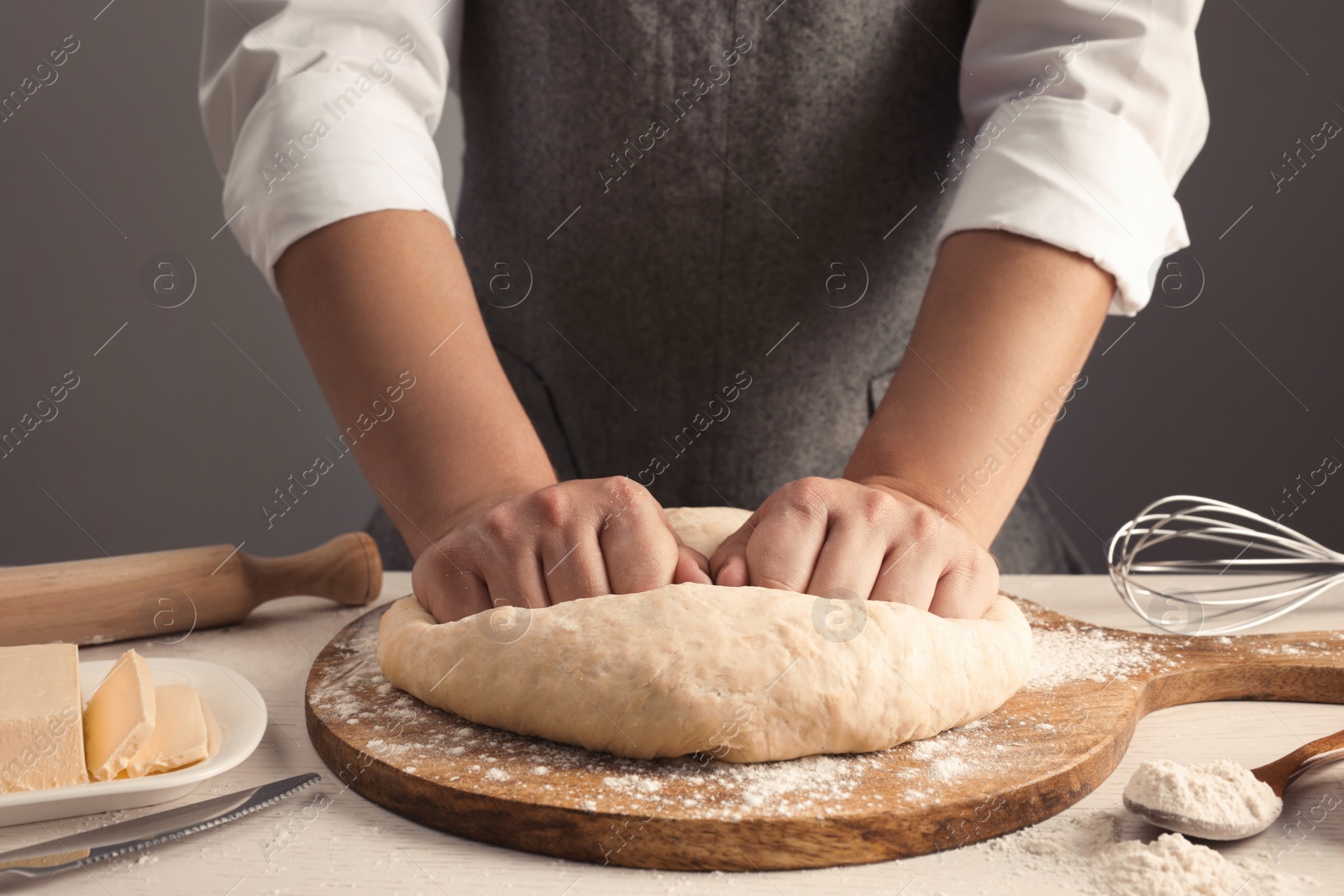 Photo of Man kneading dough at table near grey wall, closeup