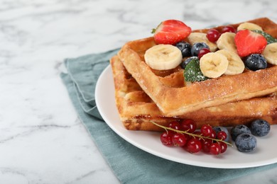 Photo of Delicious Belgian waffles with berries and banana on white marble table, closeup. Space for text