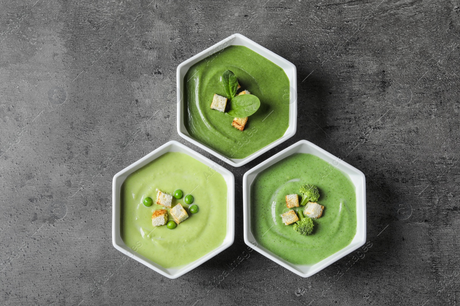 Photo of Dishes with different fresh vegetable detox soups made of green peas, broccoli and spinach on table, flat lay