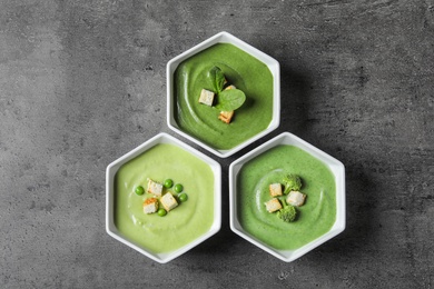 Photo of Dishes with different fresh vegetable detox soups made of green peas, broccoli and spinach on table, flat lay