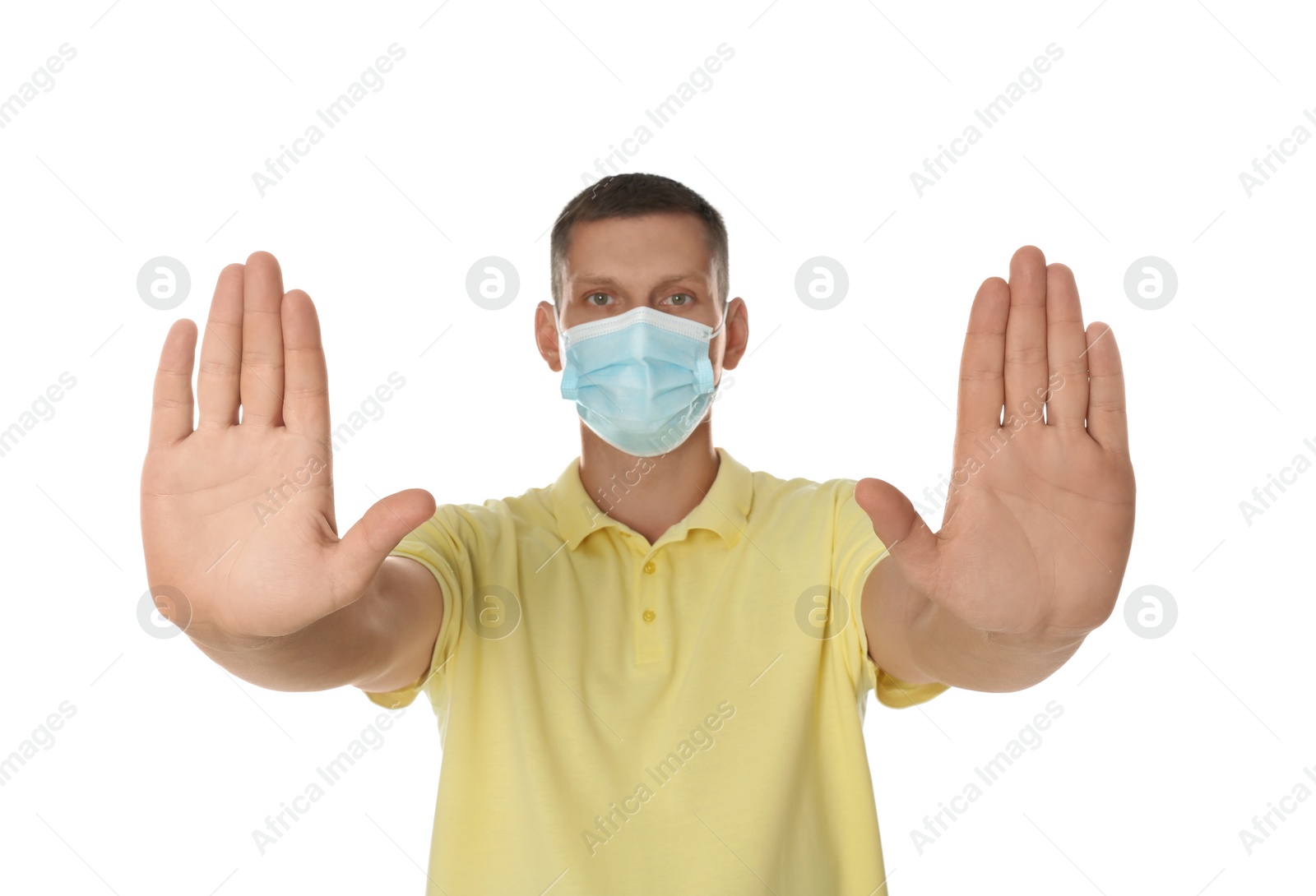 Photo of Man in protective mask showing stop gesture on white background. Prevent spreading of coronavirus