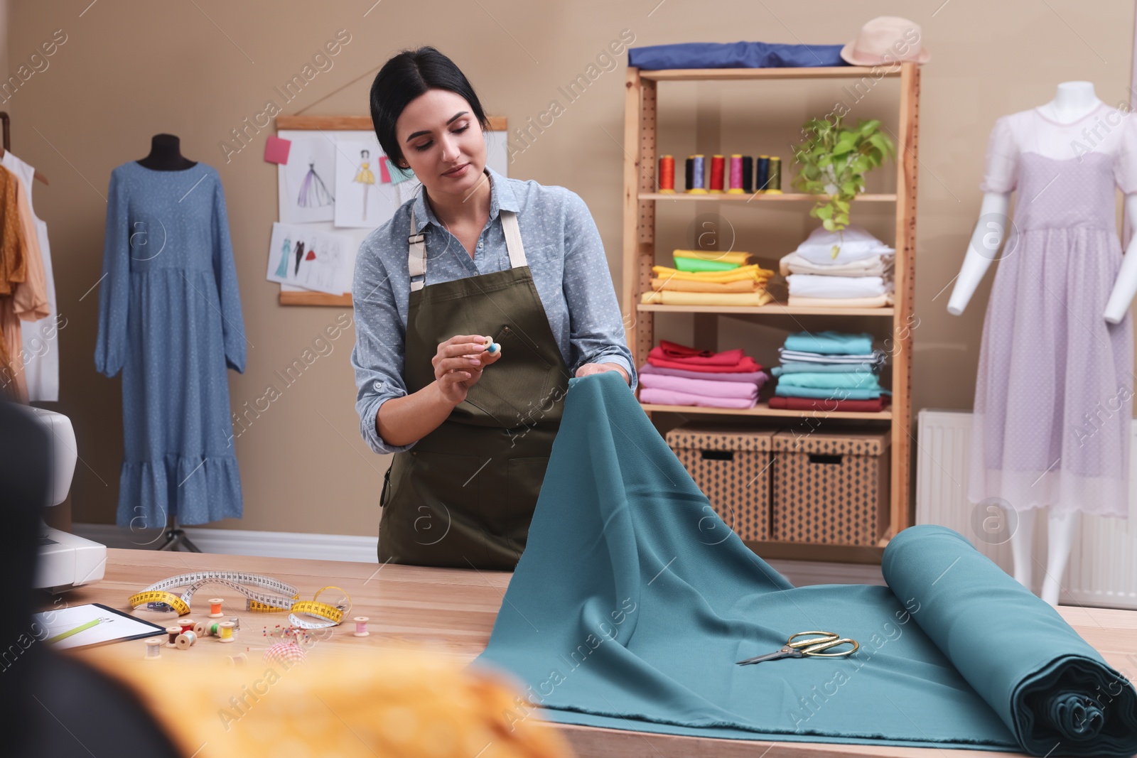 Photo of Dressmaker working with light blue fabric in atelier