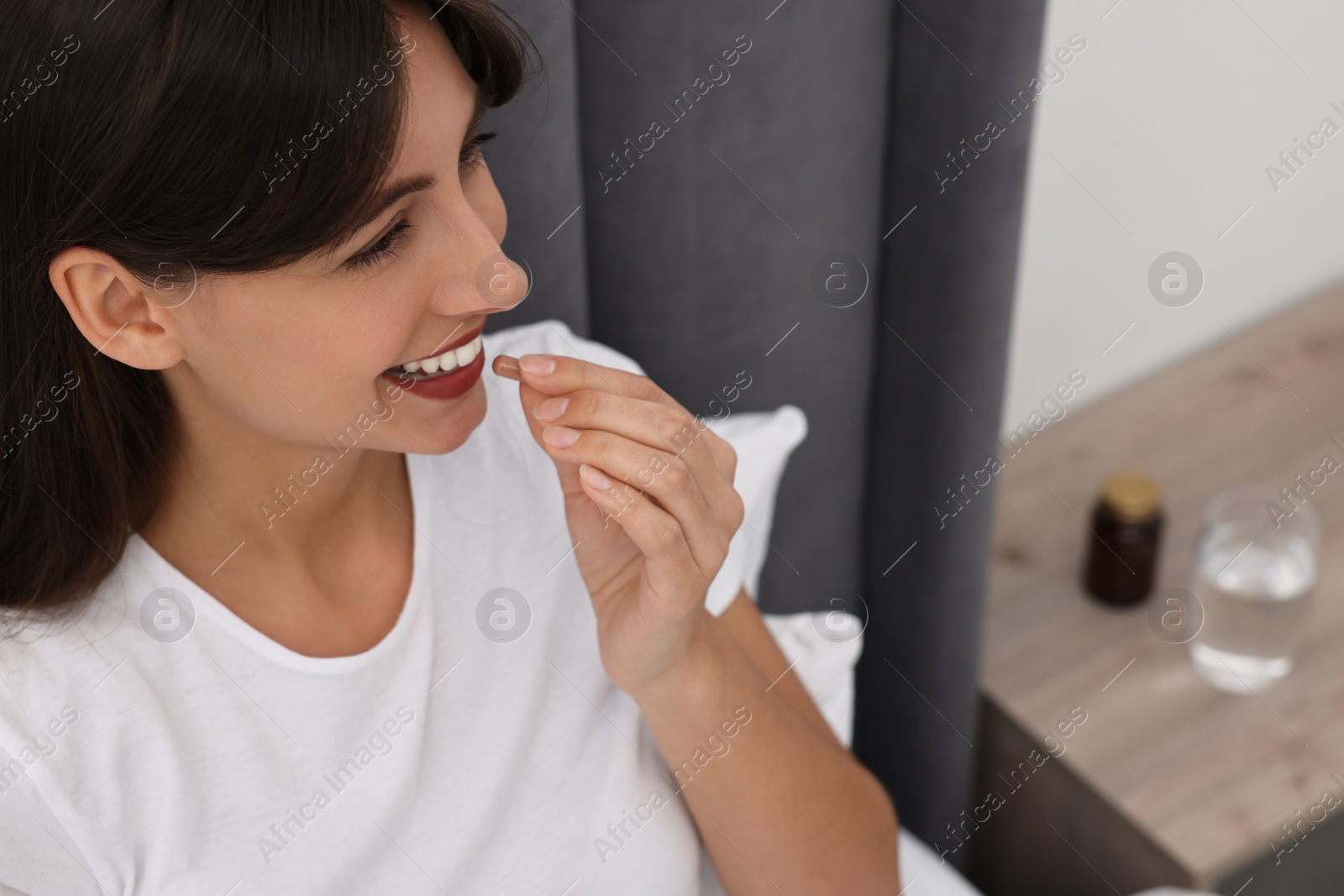 Photo of Beautiful woman taking vitamin pill at home