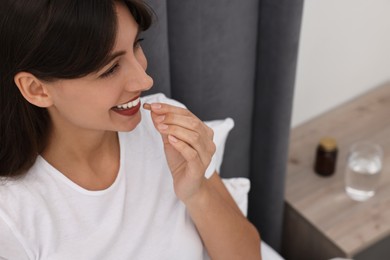 Beautiful woman taking vitamin pill at home