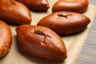 Photo of Many delicious baked patties on parchment paper, closeup