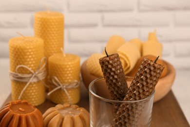 Beautiful different beeswax candles wooden table, closeup