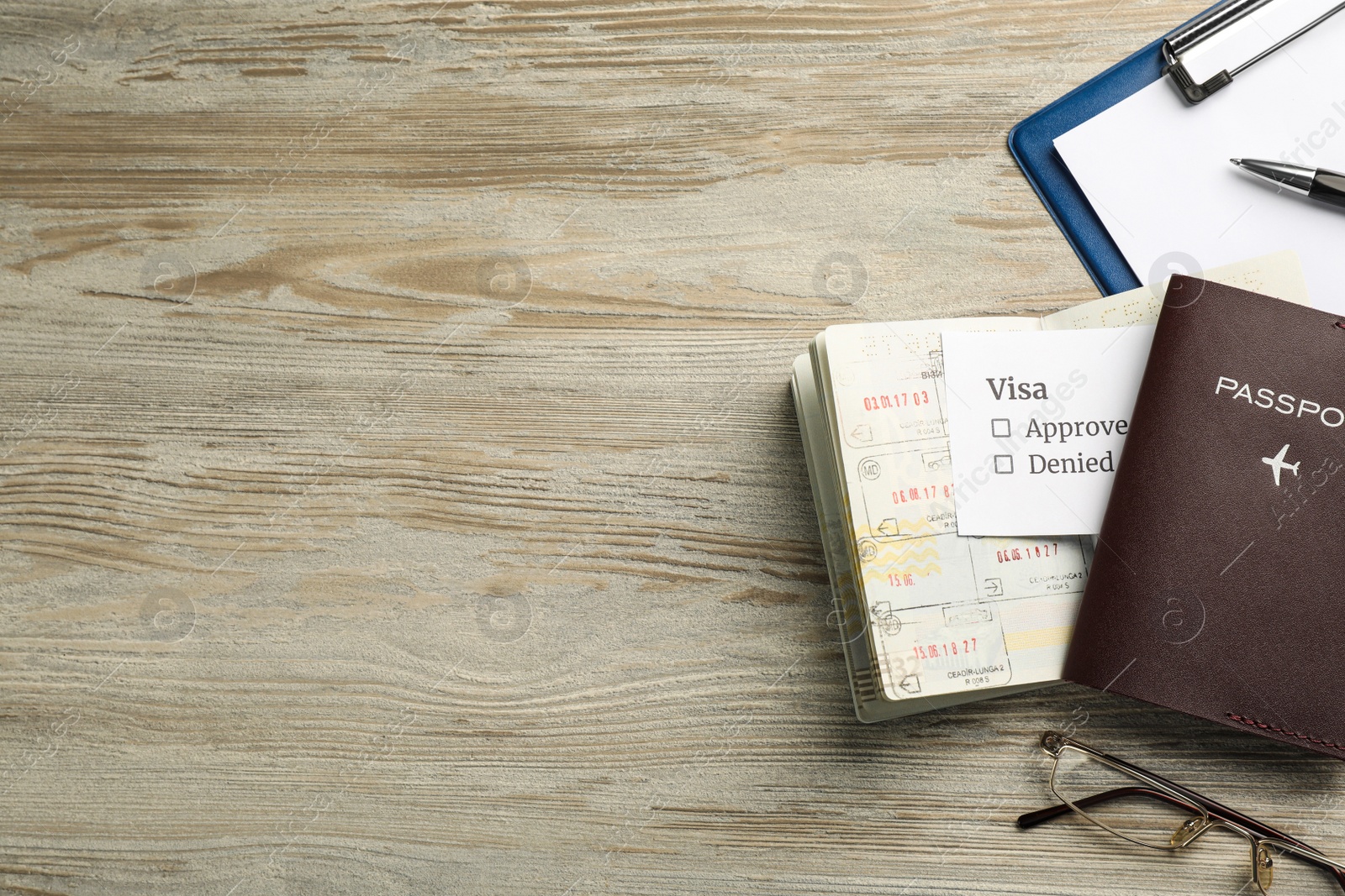 Photo of Moldova, Ceadir-Lunga - June 13, 2022: Flat lay composition with passports, pen and glasses on wooden table. Space for text