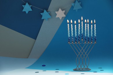 Photo of Hanukkah celebration. Menorah with burning candles on color background, space for text