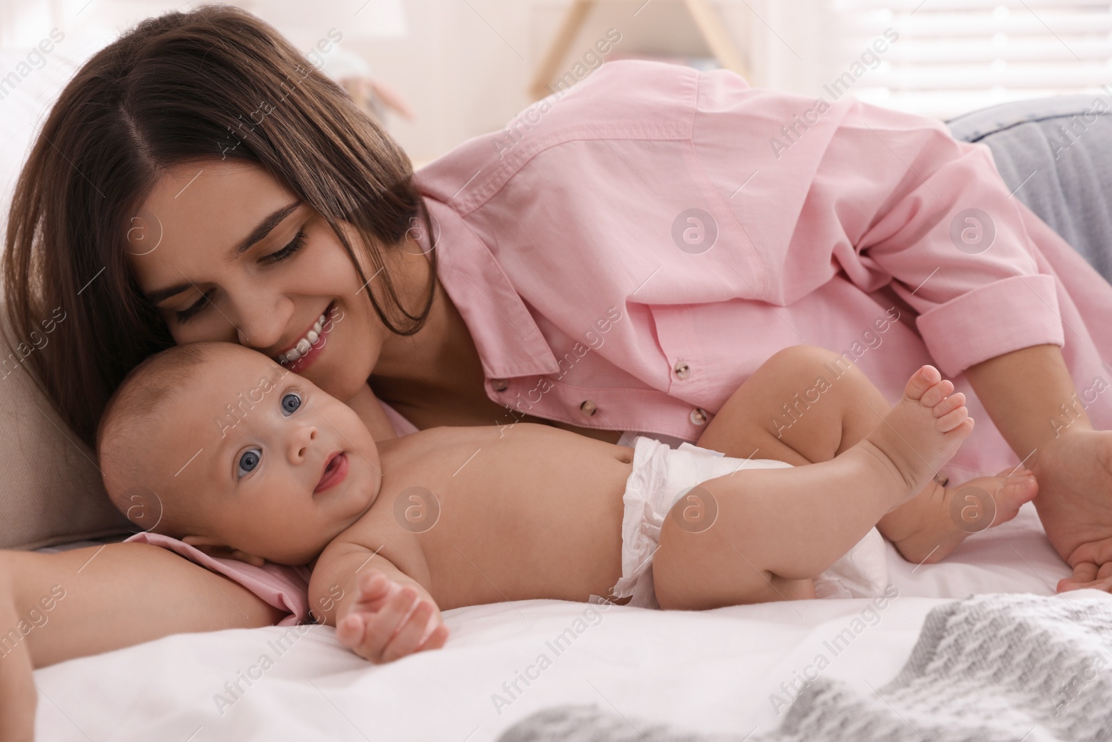 Photo of Mother with her cute baby on bed at home