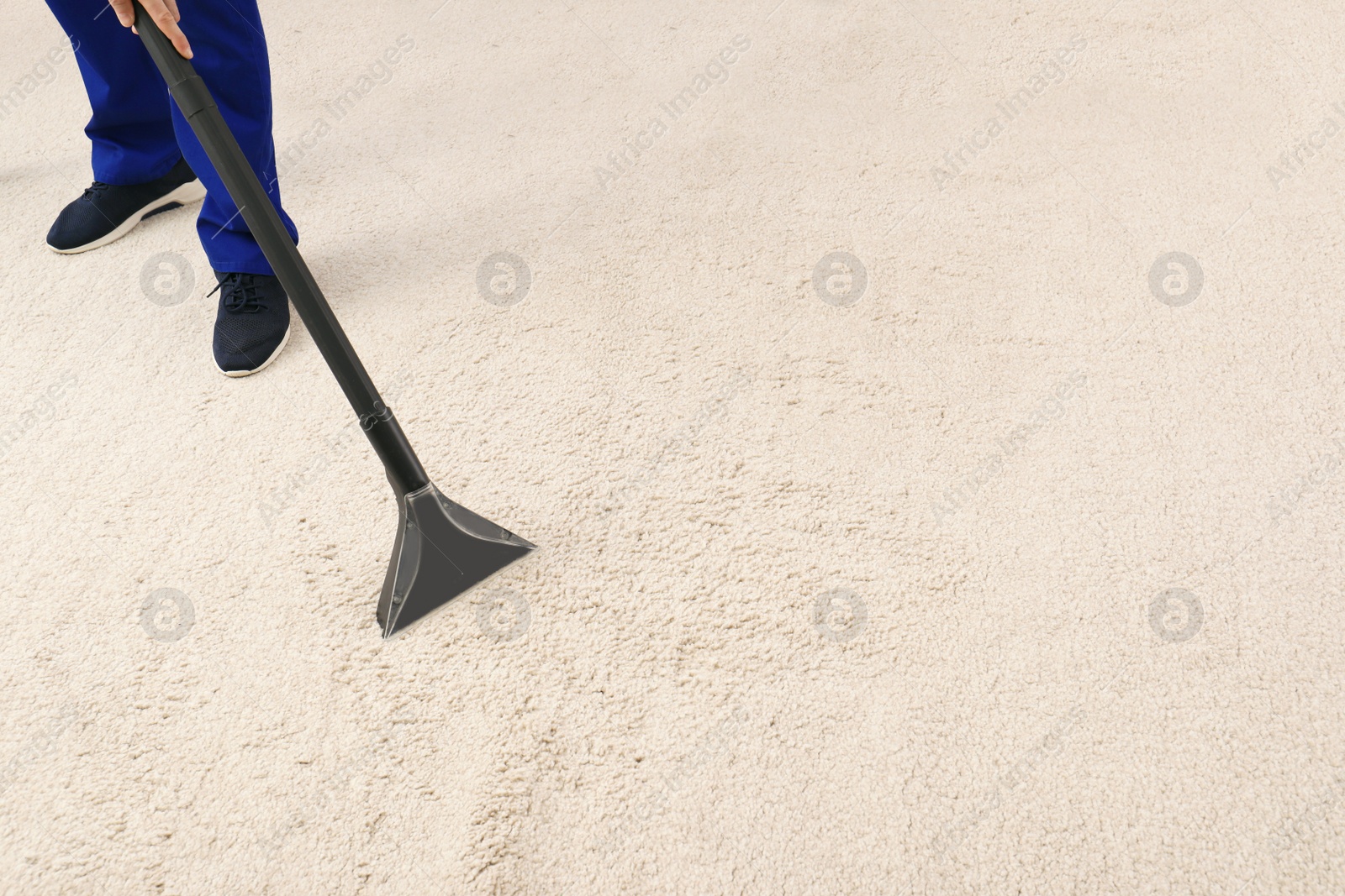 Photo of Man removing dirt from carpet with vacuum cleaner indoors, closeup. Space for text