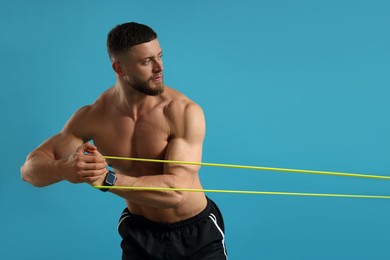 Photo of Muscular man exercising with elastic resistance band on light blue background