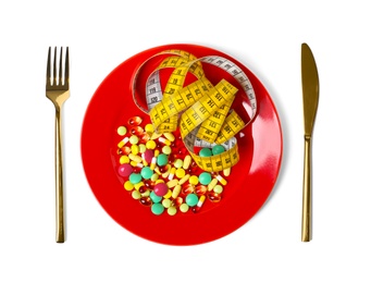 Cutlery, plate with weight loss pills and measuring tape on white background, top view