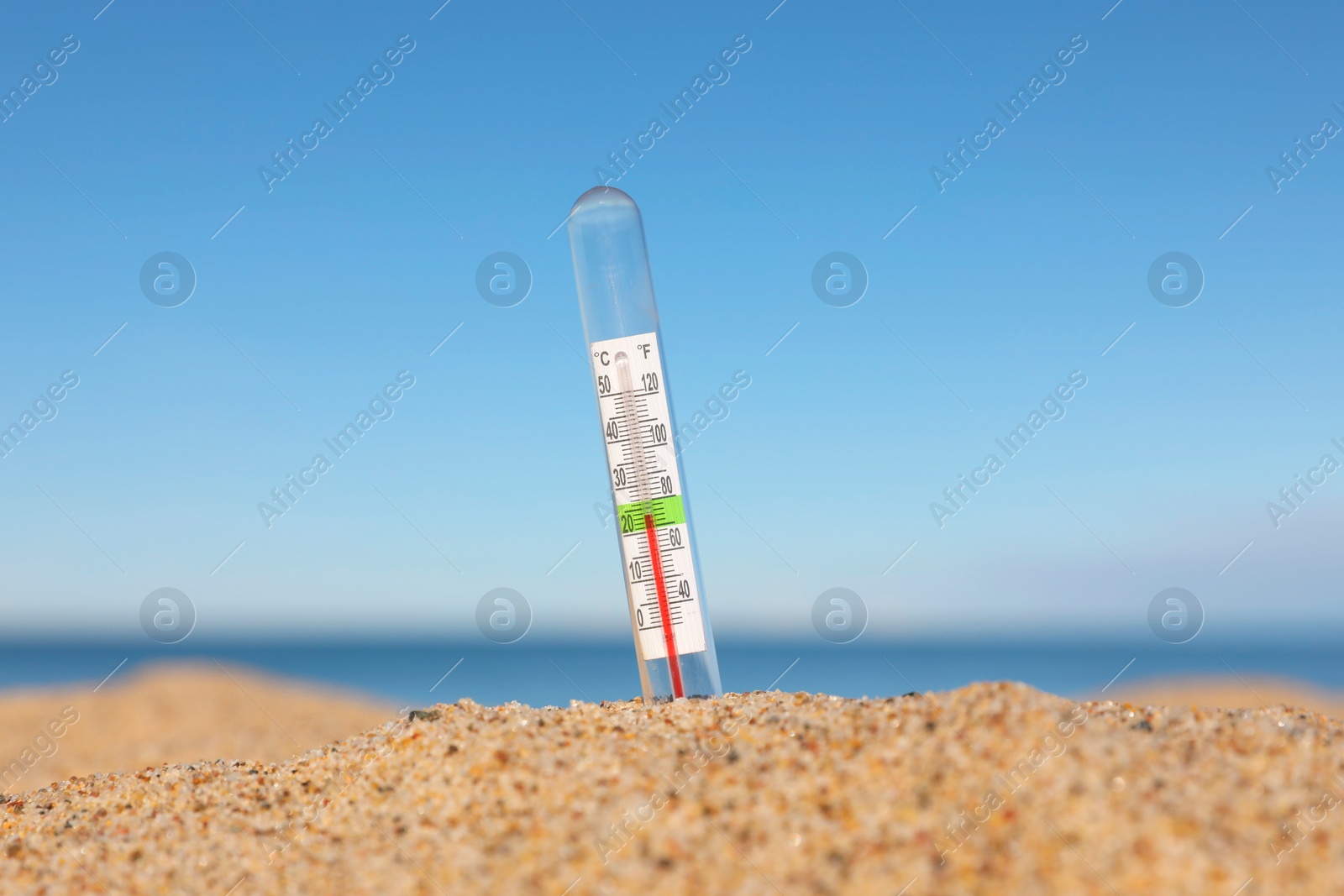 Photo of Glass weather thermometer in sand near sea