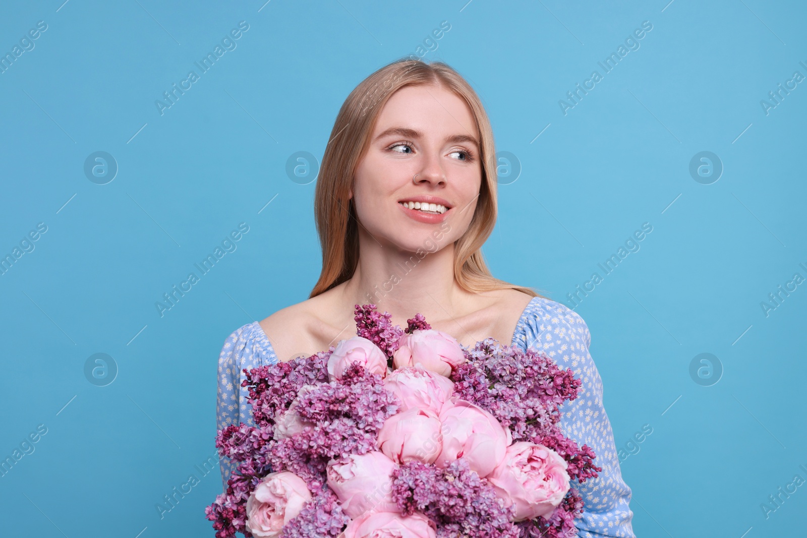 Photo of Beautiful woman with bouquet of spring flowers on light blue background