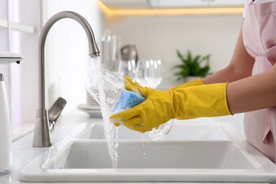 Photo of Woman washing glass in modern kitchen, closeup