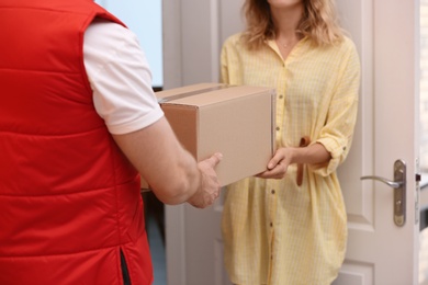 Photo of Woman receiving parcel from deliveryman indoors, closeup. Space for text