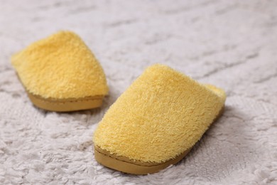 Yellow soft slippers on light carpet, closeup