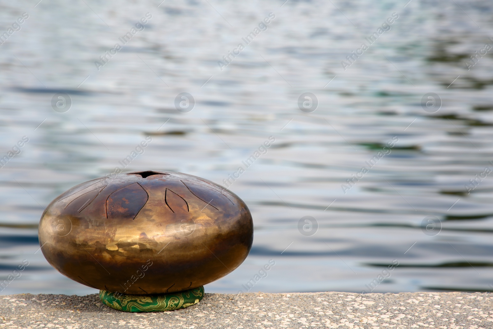 Photo of Steel tongue drum near sea, space for text. Percussion musical instrument