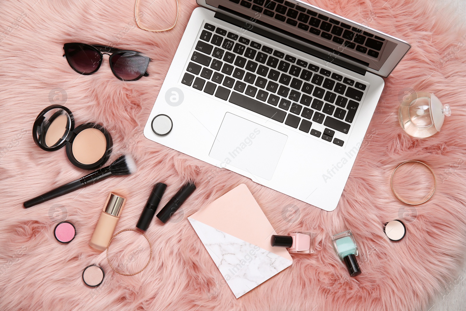 Photo of Flat lay composition with laptop, notebook and makeup products for woman on fur