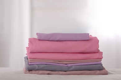 Stack of clean color folded linens on bed