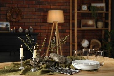 Photo of Clean dishes, stones and plants on wooden table in stylish dining room
