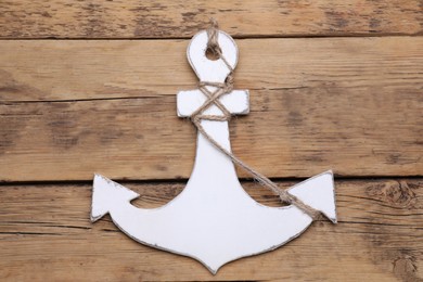 Photo of Anchor with hemp rope on wooden table, top view