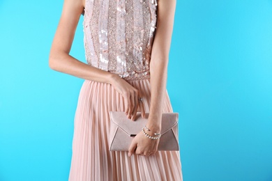 Photo of Young woman in stylish outfit with purse on color background, closeup