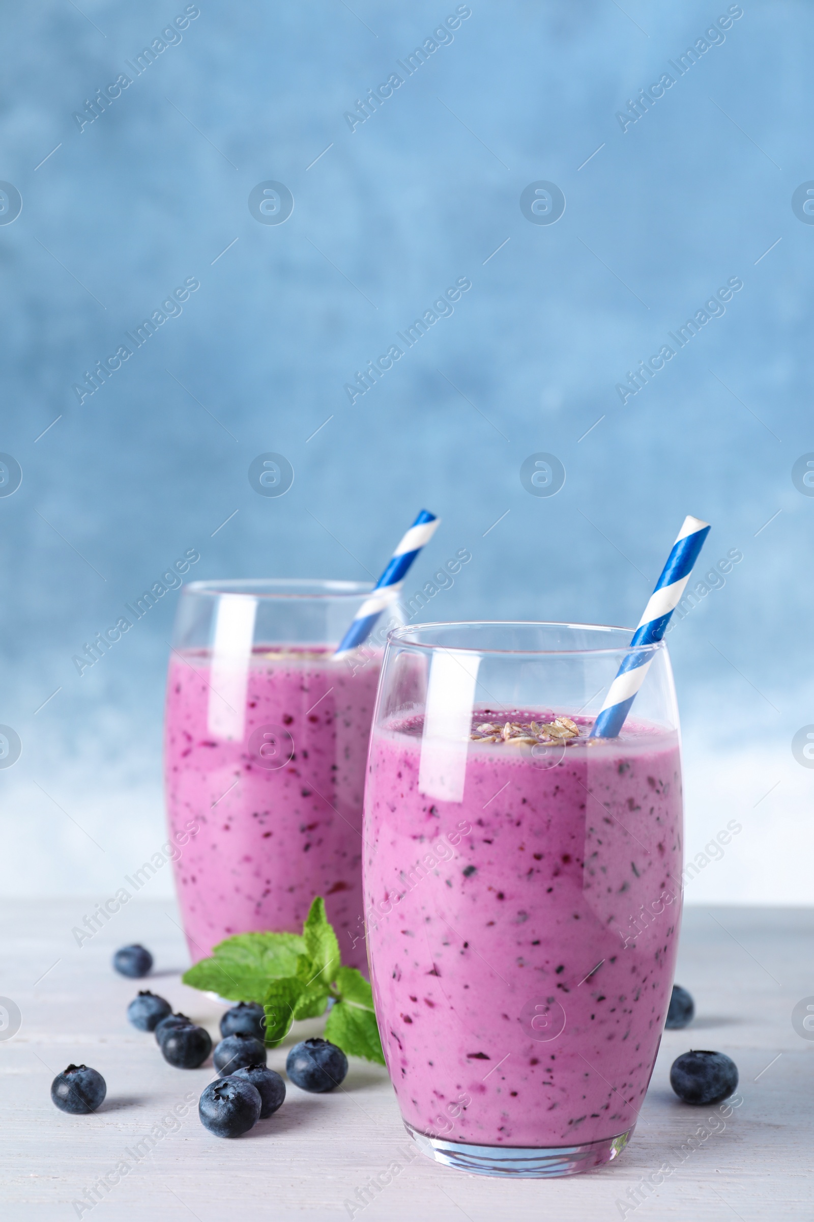 Photo of Glasses of tasty blueberry smoothie on white wooden table, space for text