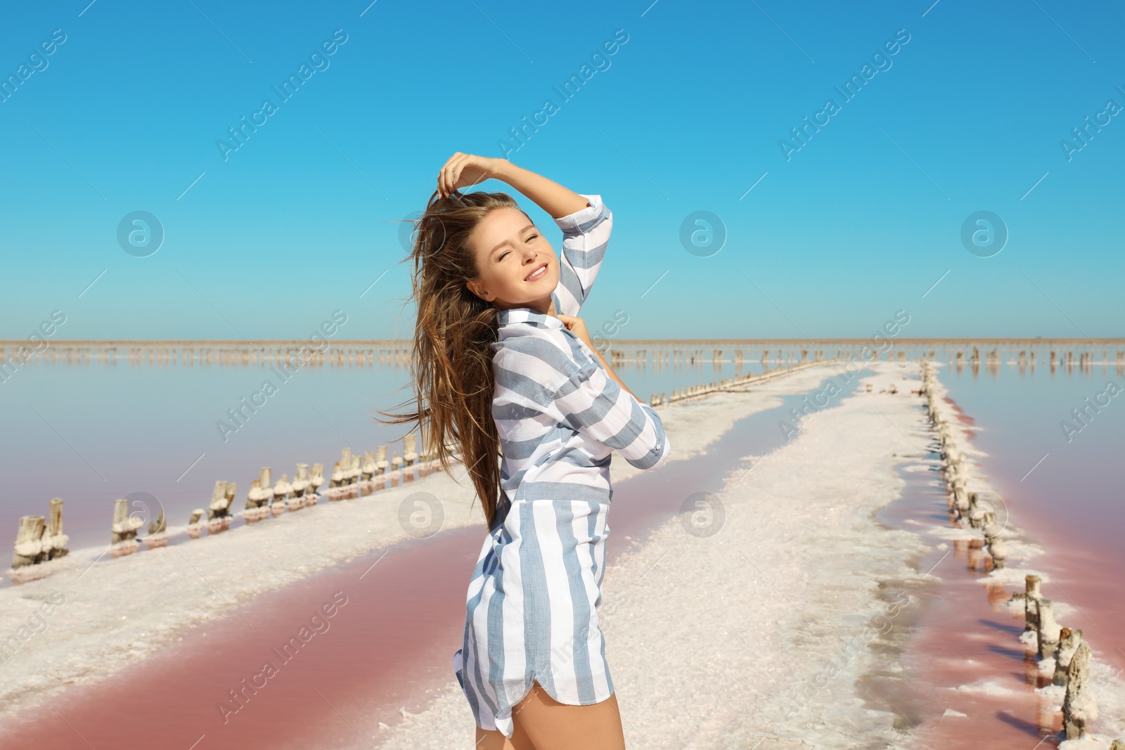 Photo of Beautiful woman posing near pink lake on summer day