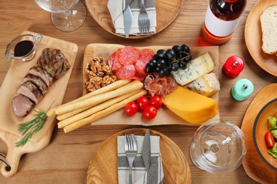 Photo of Delicious food and wine served for dinner on wooden table, flat lay