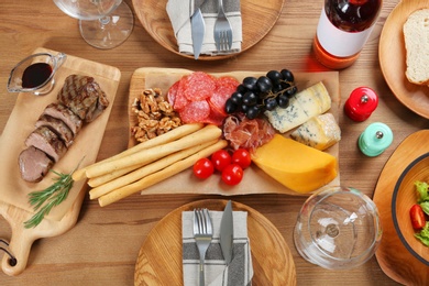 Delicious food and wine served for dinner on wooden table, flat lay