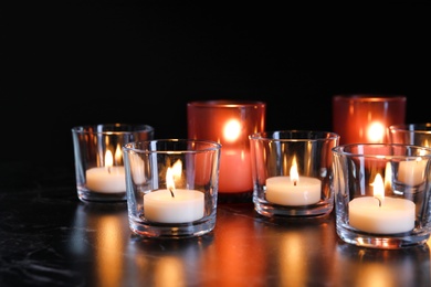 Burning candles on table in darkness. Funeral symbol