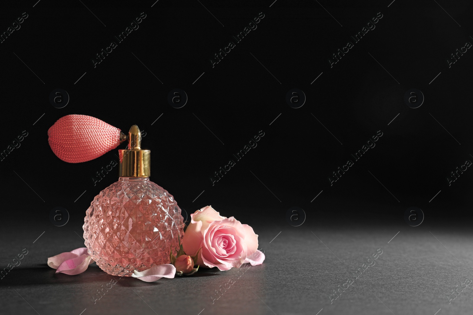 Photo of Vintage bottle of perfume and beautiful flower on black background, space for text