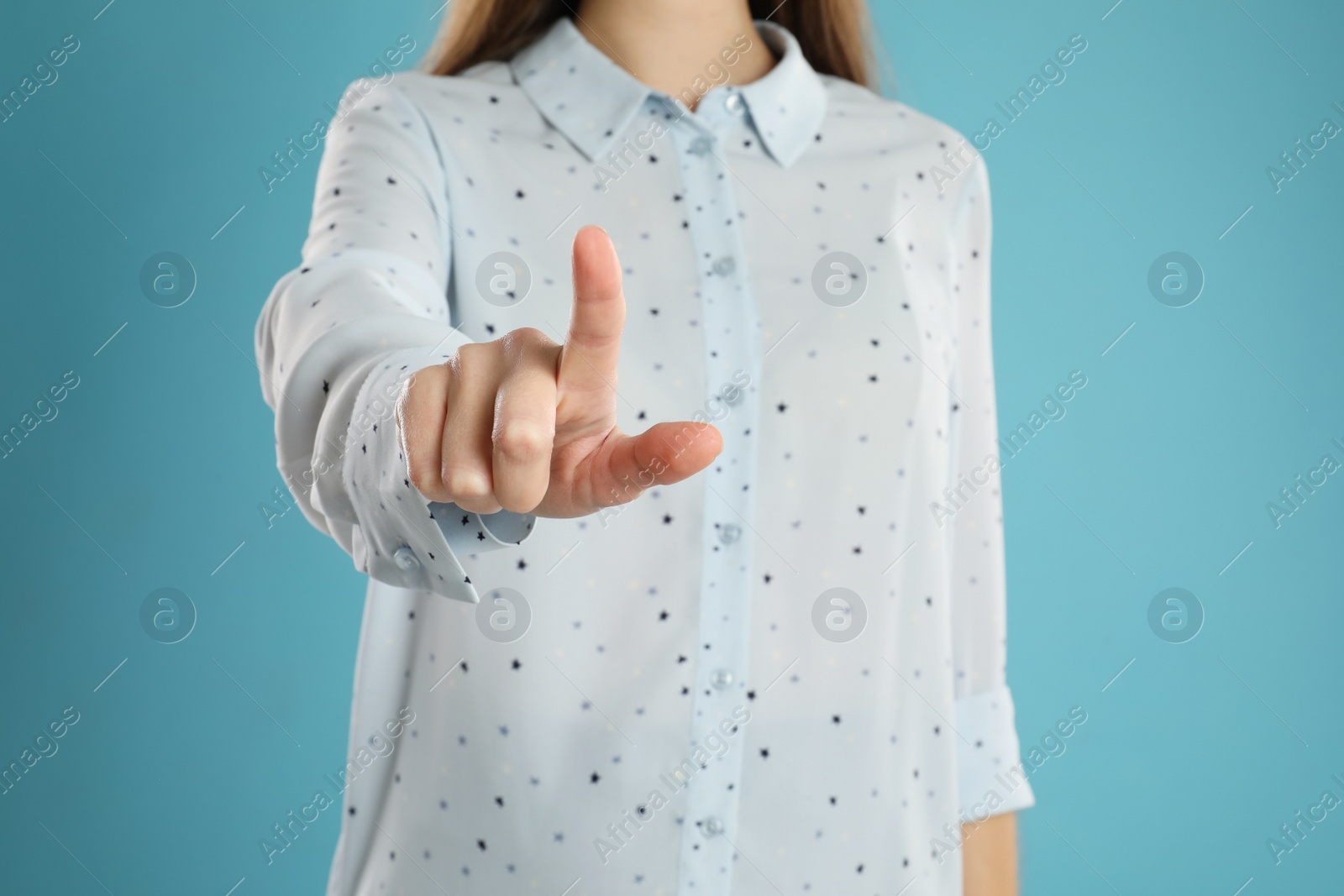 Photo of Woman pointing at something on light blue background, closeup. Finger gesture