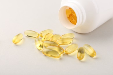 Photo of Vitamin capsules and bottle on light grey background, closeup